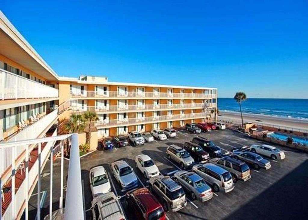 Quality Inn Oceanfront في شاطئ أورموند: موقف سيارات خاص بالفندق مع وقوف السيارات أمام المحيط