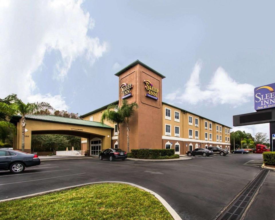 a hotel with cars parked in a parking lot at Sleep Inn & Suites Orlando International Airport in Orlando