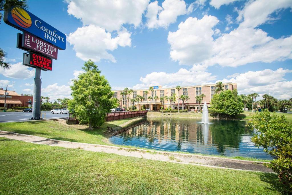 a sign for a hotel with a pond and a fountain at Comfort Inn Kissimmee by the Parks in Orlando