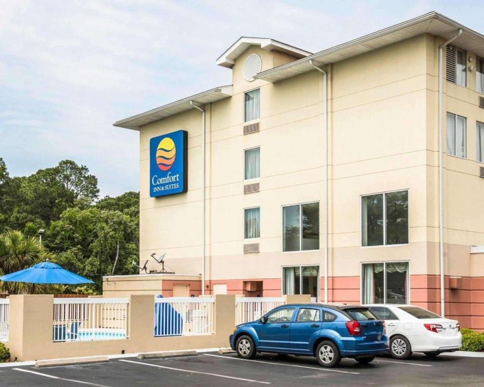 Un bâtiment avec une voiture bleue garée devant. dans l'établissement Comfort Inn & Suites Panama City - St Andrew, à Panama City