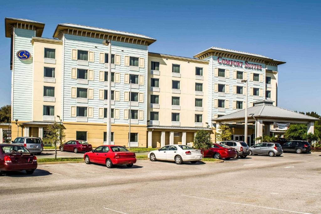 a large hotel with cars parked in a parking lot at Comfort Suites Palm Bay - Melbourne in Palm Bay