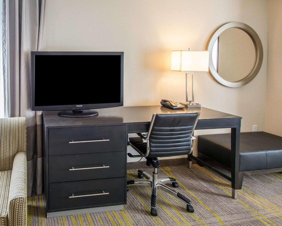 a desk with a television and a chair in a hotel room at Comfort Suites Miami Airport North in Miami