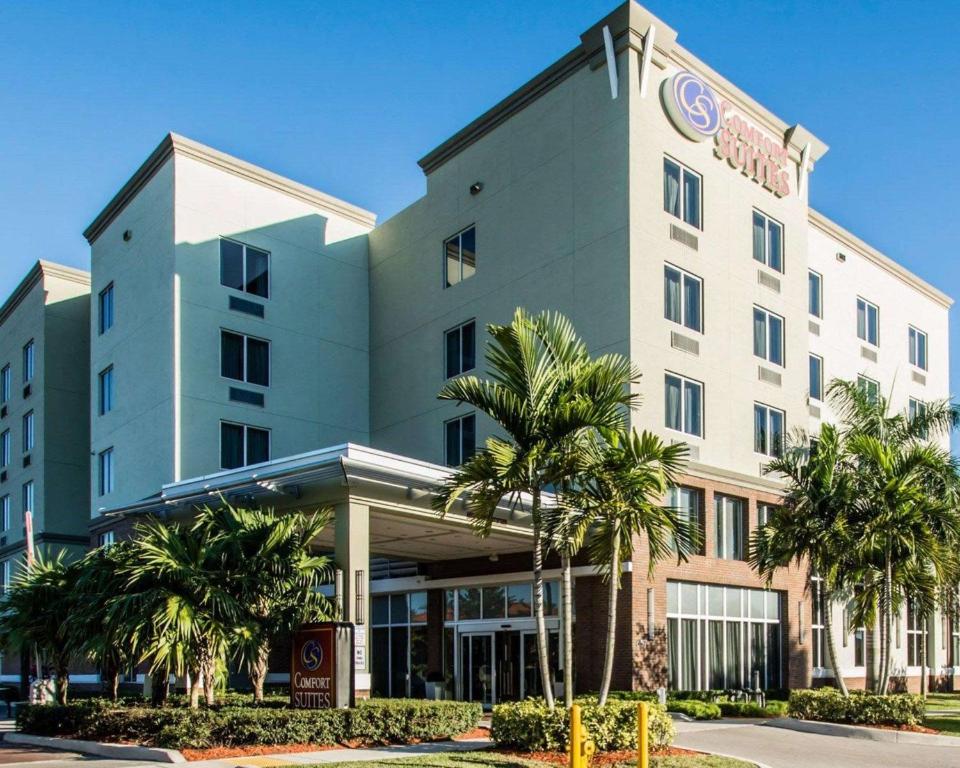 a hotel building with palm trees in front of it at Comfort Suites Miami Airport North in Miami