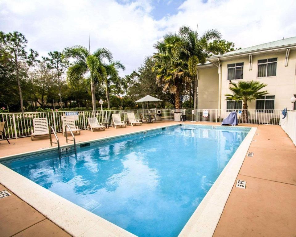 une grande piscine avec des chaises et un bâtiment dans l'établissement Sleep Inn at PGA Village, à Port Sainte-Lucie