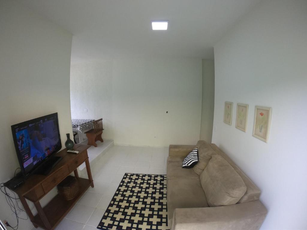 ein Wohnzimmer mit einem Sofa und einem TV in der Unterkunft Lugar tranquilo na praia in Ubatuba