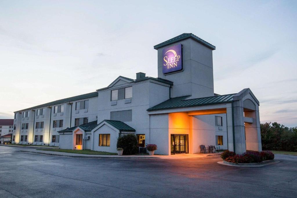 a large white building with a neon sign on it at Sleep Inn Douglasville in Douglasville