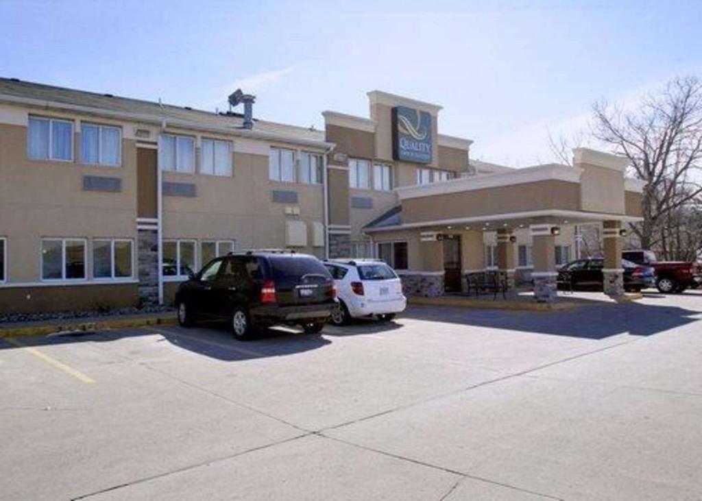 two cars parked in a parking lot in front of a hotel at Quality Inn & Suites Des Moines Airport in Des Moines