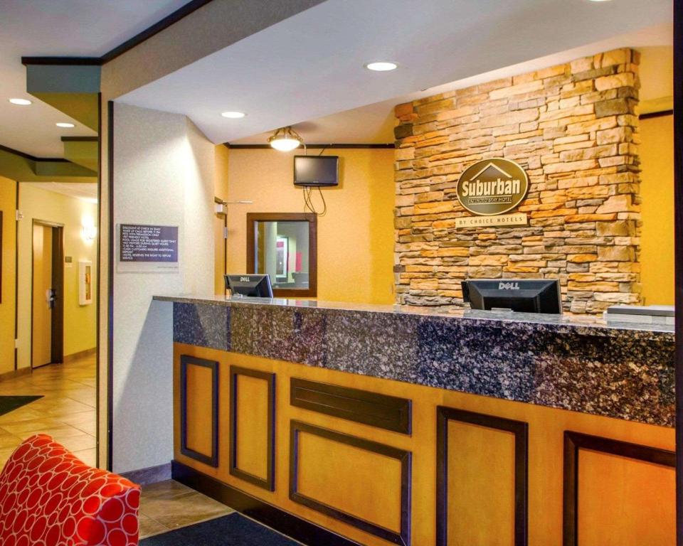 a hotel lobby with a bar with a stone wall at Suburban Studios Cedar Falls in Cedar Falls