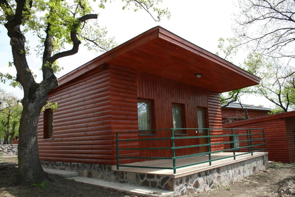 eine Blockhütte mit einer Veranda und einem Baum in der Unterkunft Mátra Kemping Apartmanok in Matrafured