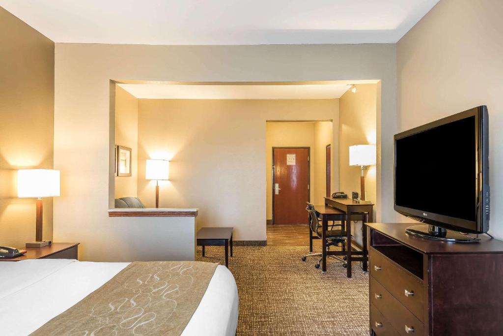 a hotel room with a bed and a flat screen tv at Comfort Suites North in Fort Wayne