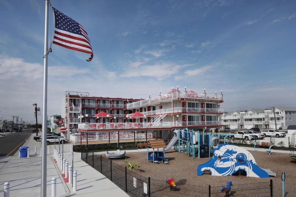 Matador Oceanfront Resort في شمال وايلدوود: مبنى مع علم أمريكي وملعب