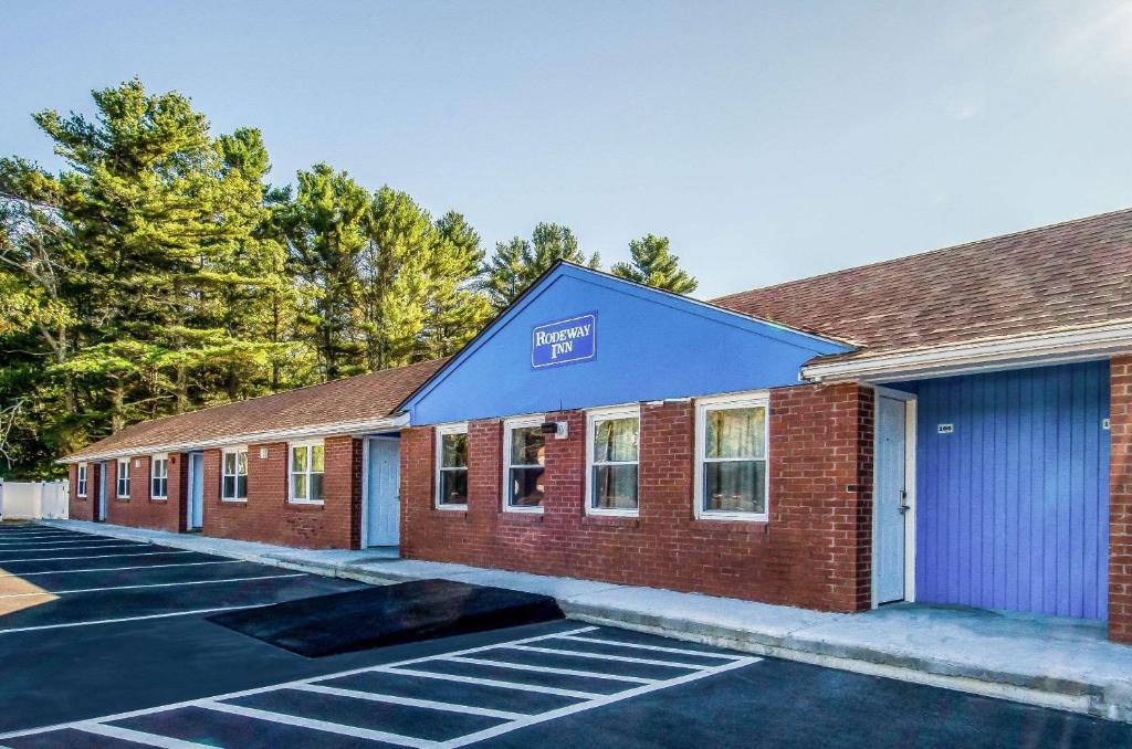 a building with a blue roof and a parking lot at Rodeway Inn Middleboro-Plymouth in Middleboro