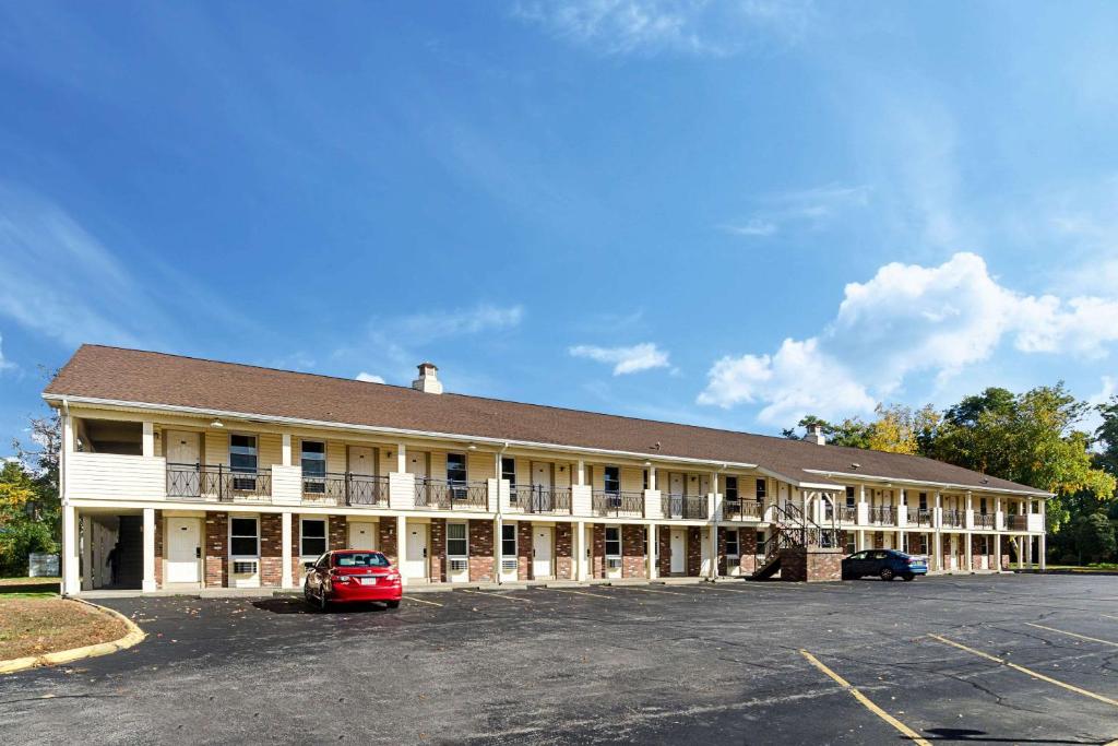 ein großes Gebäude mit einem auf einem Parkplatz geparkten Auto in der Unterkunft Econo Lodge Sturbridge Route 20 in Sturbridge