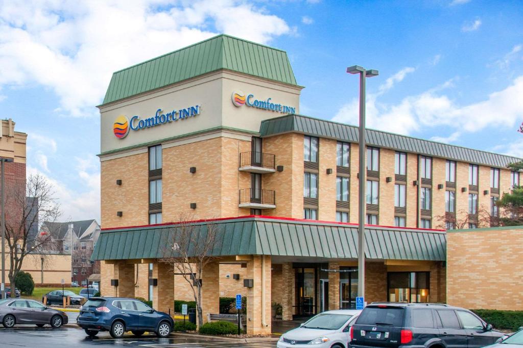 Comfort Inn MSP Airport - Mall of America في بلومنغتون: مبنى فيه سيارات متوقفة في موقف للسيارات