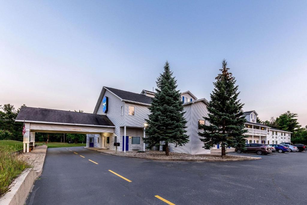 a large white building with trees in the parking lot at Rodeway Inn in Ludington