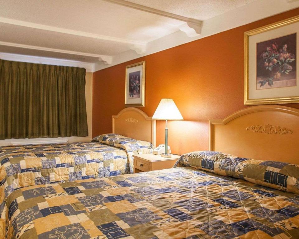 duas camas num quarto de hotel com paredes cor de laranja em Relax Inn Saint Charles em St. Charles