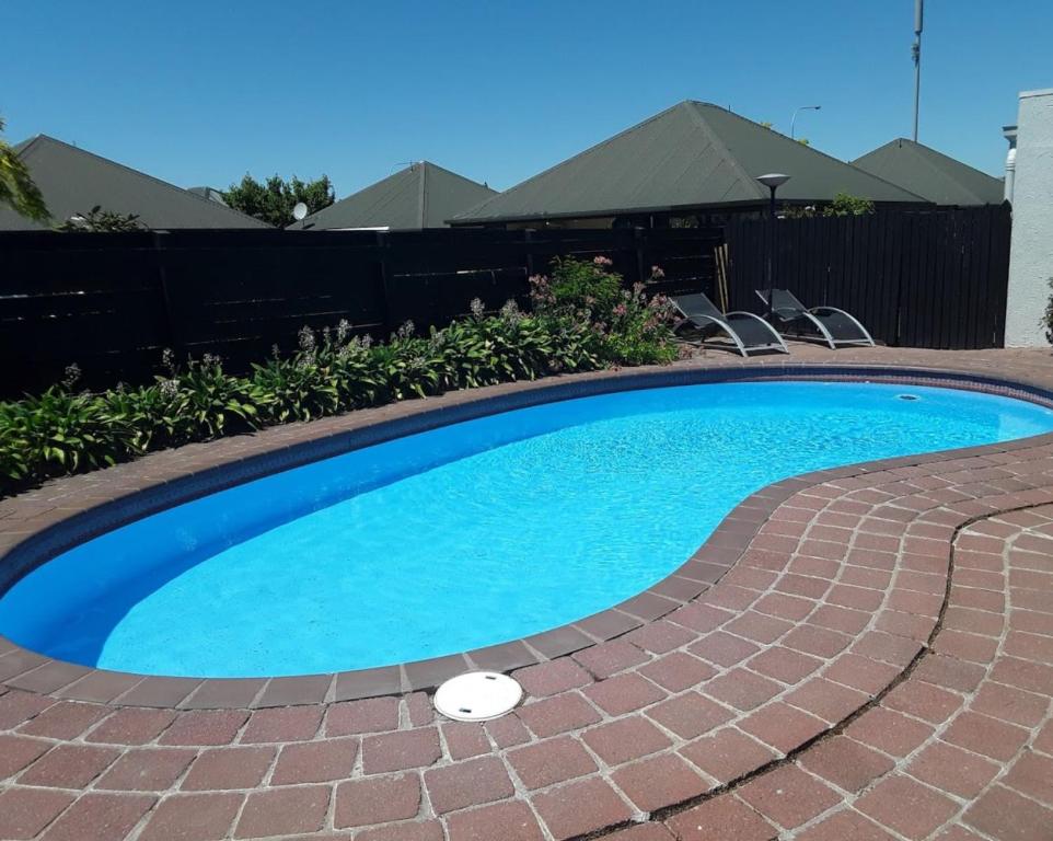 a swimming pool with a brick pathway around it at Sundowner Motel in Blenheim