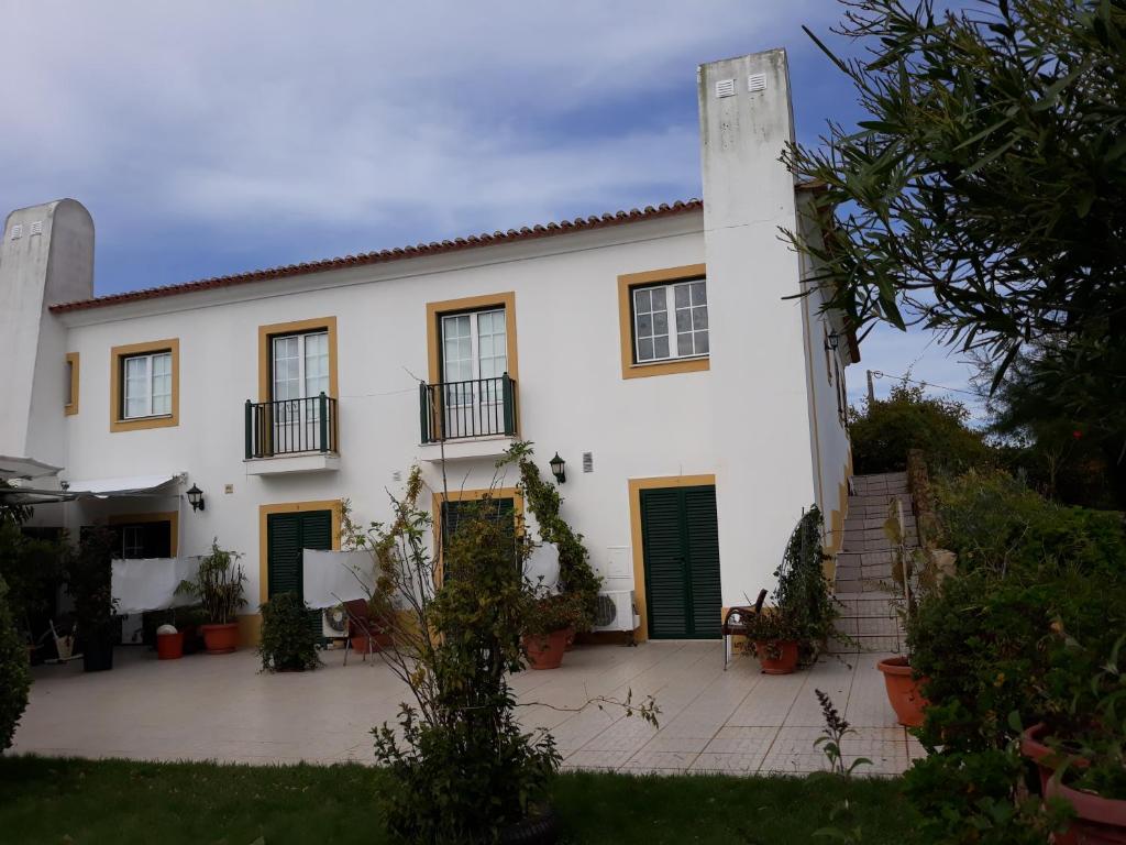 een wit huis met groene deuren en een binnenplaats bij A Deolinda in Santiago do Cacém