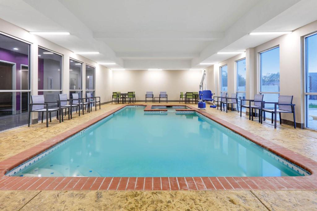 a large swimming pool with tables and chairs in a building at Wingate by Wyndham Corpus Christi in Corpus Christi