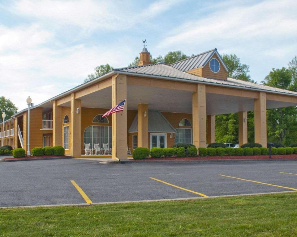 a large yellow building with a flag in a parking lot at Quality Inn Andrews in Andrews