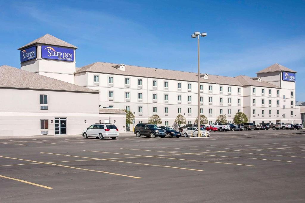 un gran edificio blanco con coches aparcados en un aparcamiento en Sleep Inn & Suites Conference Center and Water Park, en Minot