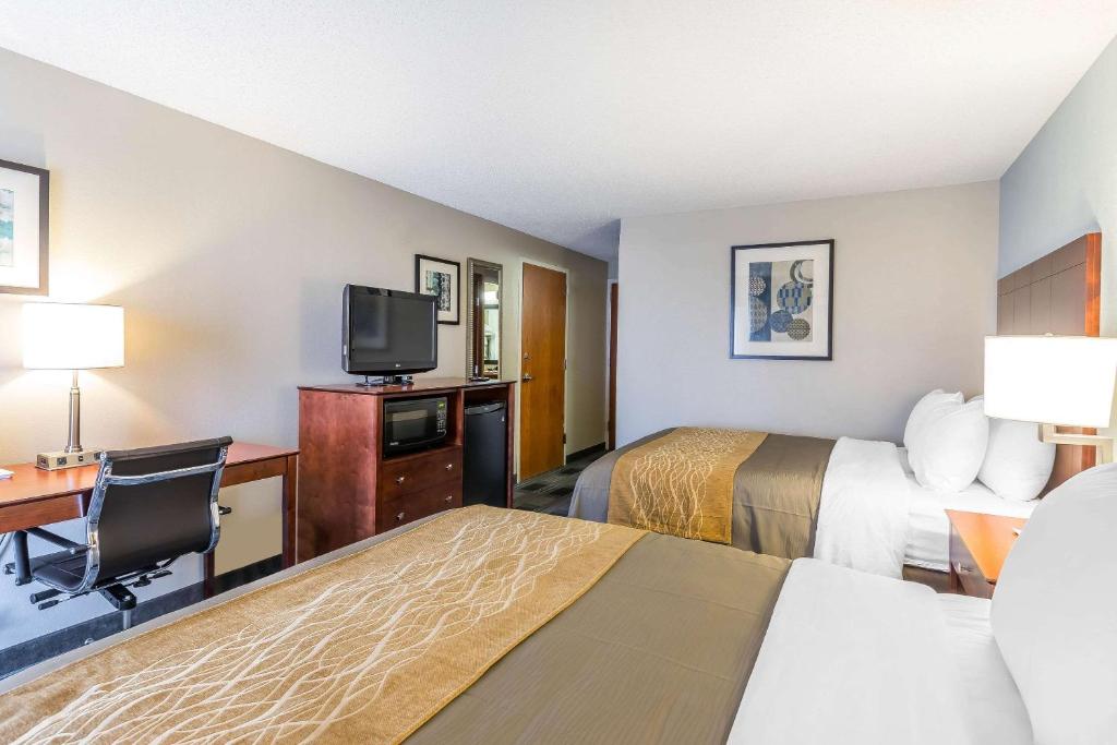 a hotel room with two beds and a desk and a tv at Comfort Inn SW Omaha I-80 in Omaha