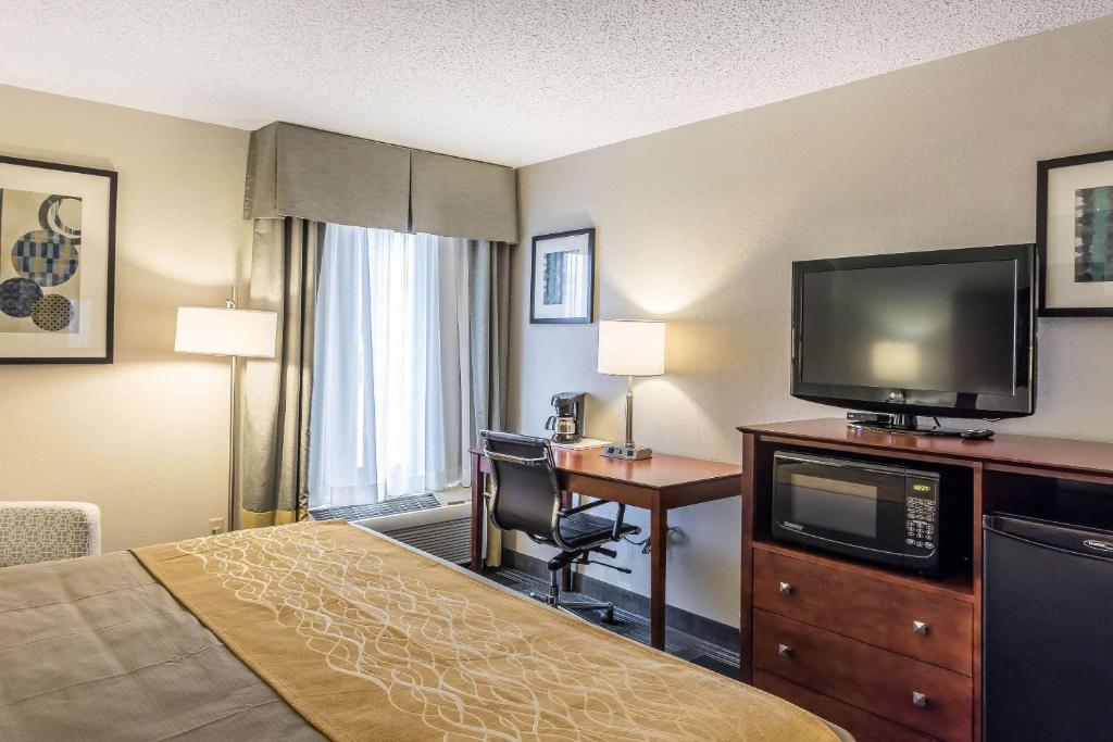 a hotel room with a bed and a desk and a television at Comfort Inn SW Omaha I-80 in Omaha