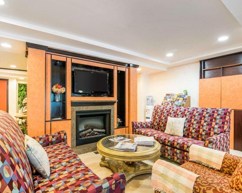 ein Wohnzimmer mit Sofas, einem TV und einem Kamin in der Unterkunft Quality Inn in Ashland