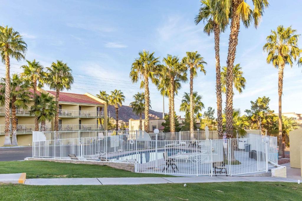 uma cerca branca com palmeiras em frente a um edifício em Lake Mead Inn em Boulder City