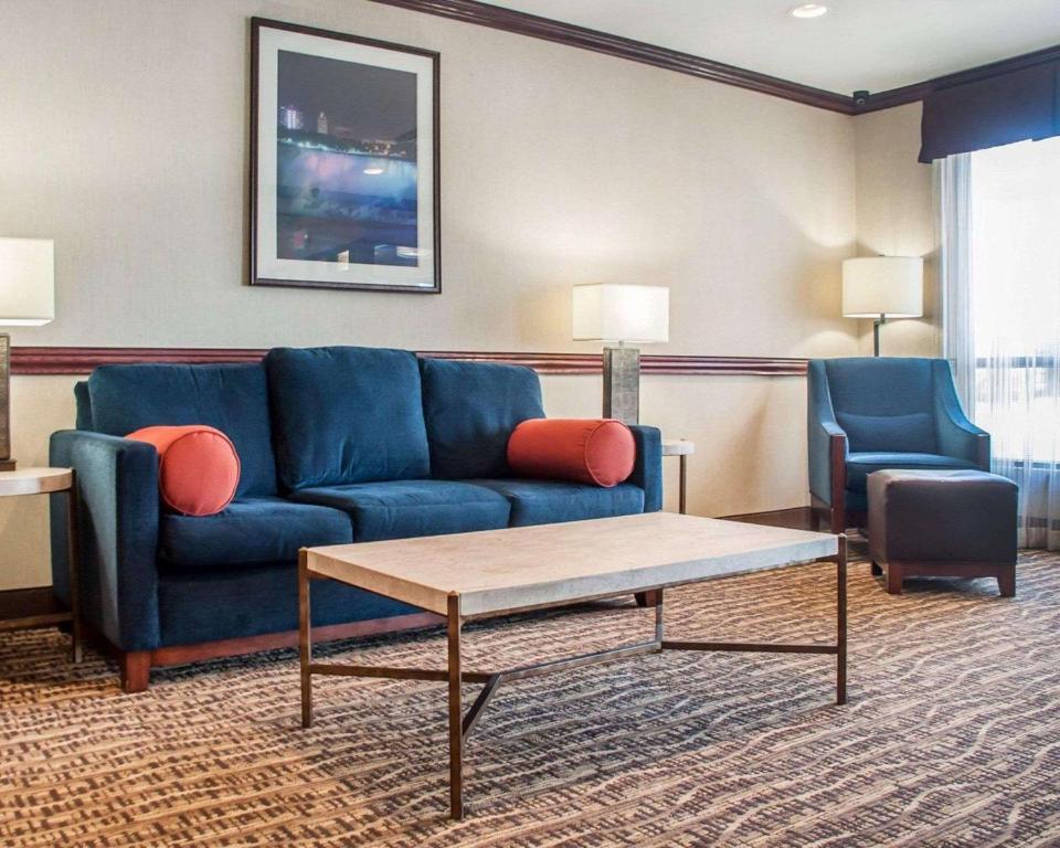 a living room with a blue couch and two chairs at Quality Inn Near Walden Galleria Mall in Cheektowaga