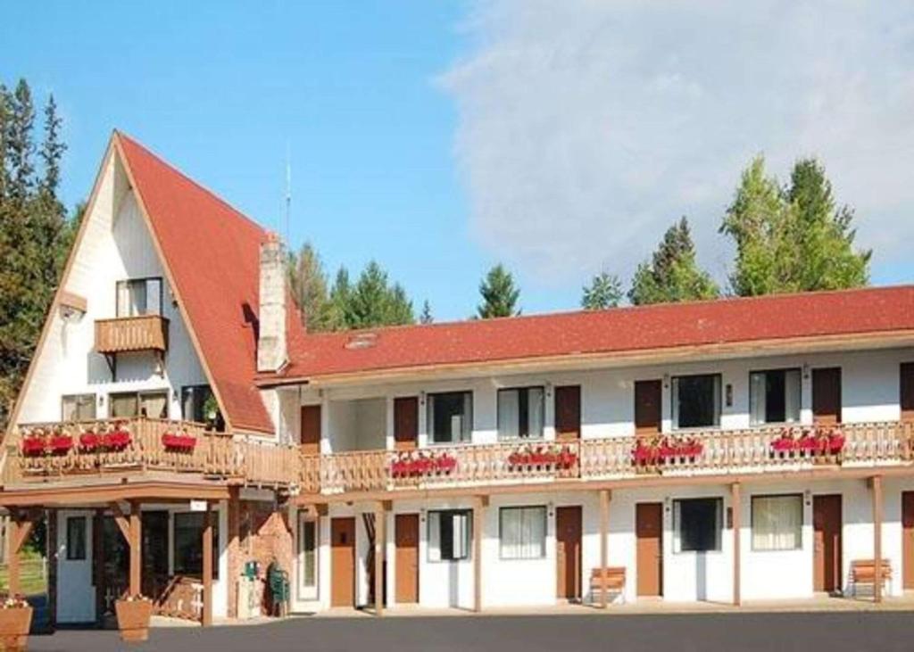 a large white building with a red roof at Rodeway Inn Lake Placid in Lake Placid