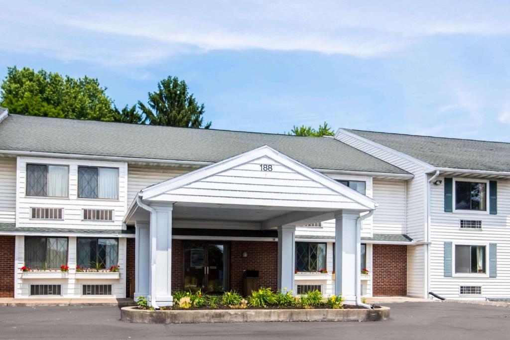 a white building with a garage at Quality Inn Cortland - University Area in Cortland