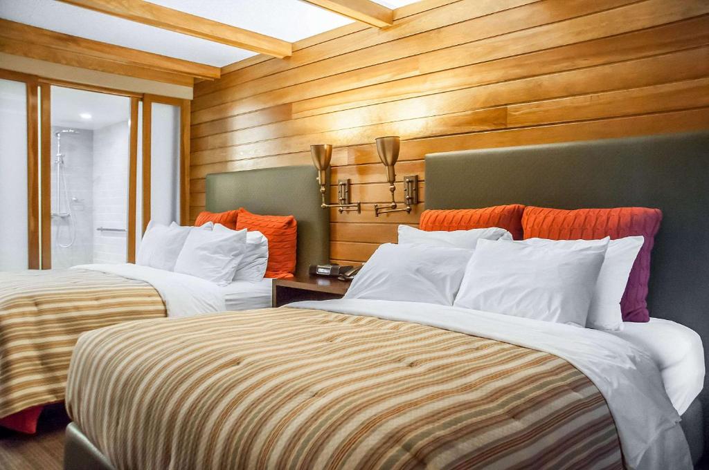 two beds in a room with wooden walls at Comfort Inn The Pointe in Niagara Falls