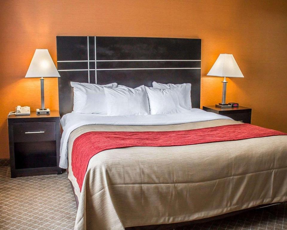 a large bed in a hotel room with two lamps at Norwood Inn & Suites Columbus in Columbus