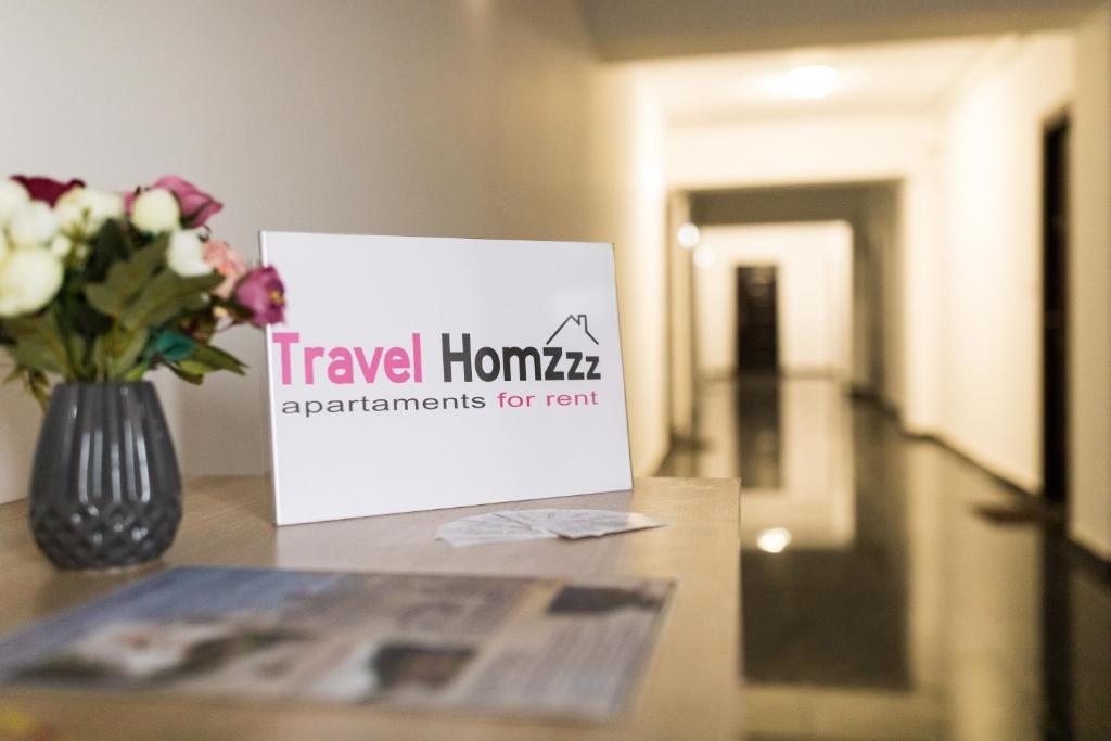 un jarrón de flores y un cartel en una mesa en Travel Homzzz Apartments en Târgu Mureș