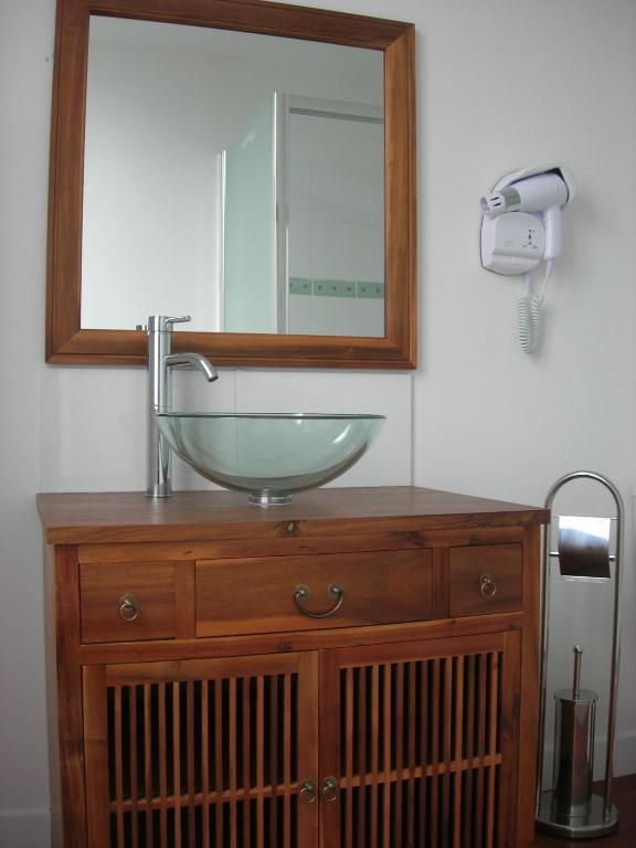 a bathroom sink with a mirror on top of a wooden dresser at Hotel Mona Lisa in La Baule