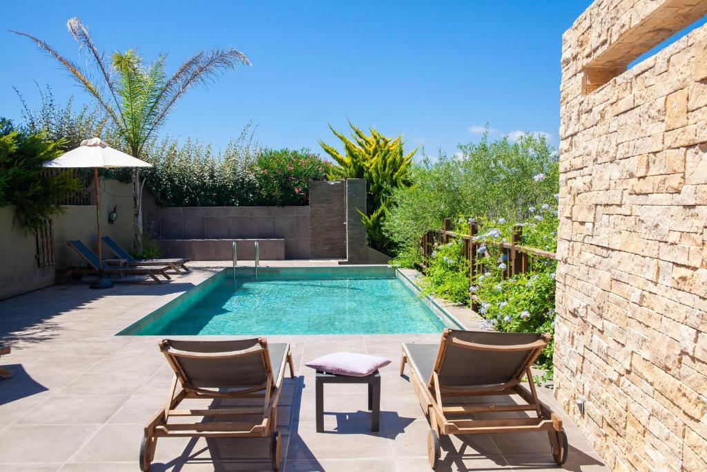 een zwembad in een tuin met 2 stoelen en een tafel bij Résidence Guddelmoni in Propriano