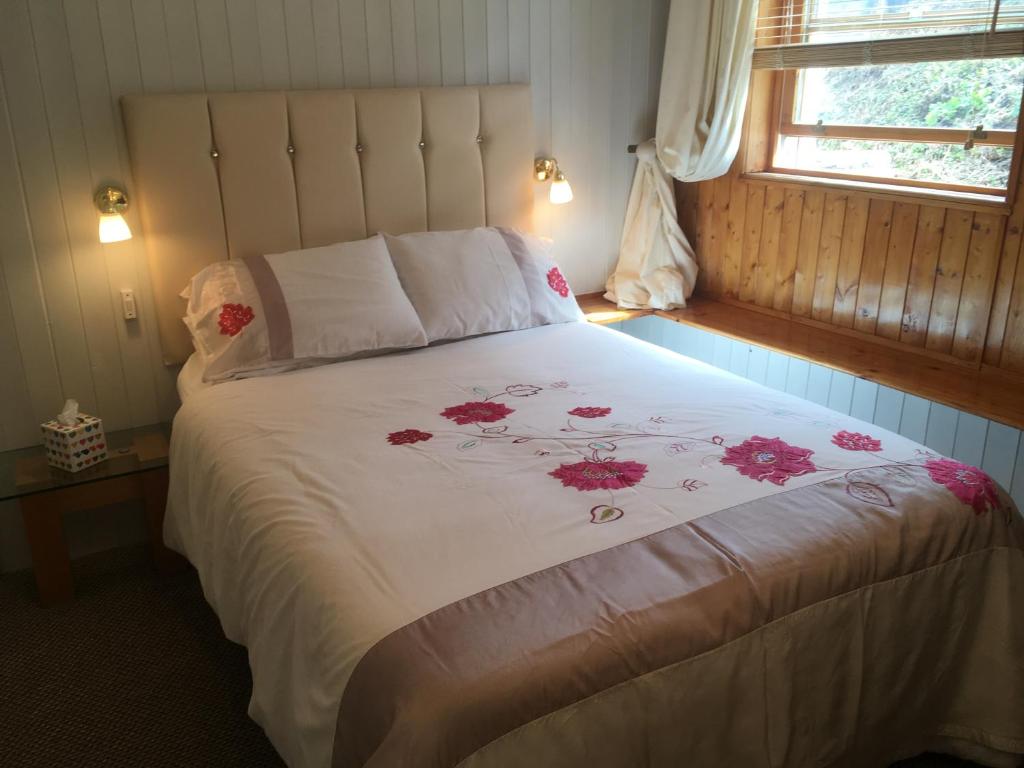 a bedroom with a large white bed with red flowers on it at The Folly Hotel in North Berwick