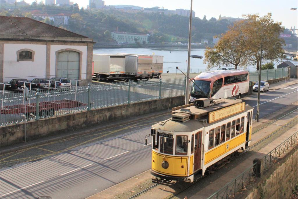 um comboio amarelo nos carris ao lado de uma estrada em AlfandegaPorto Apartments no Porto