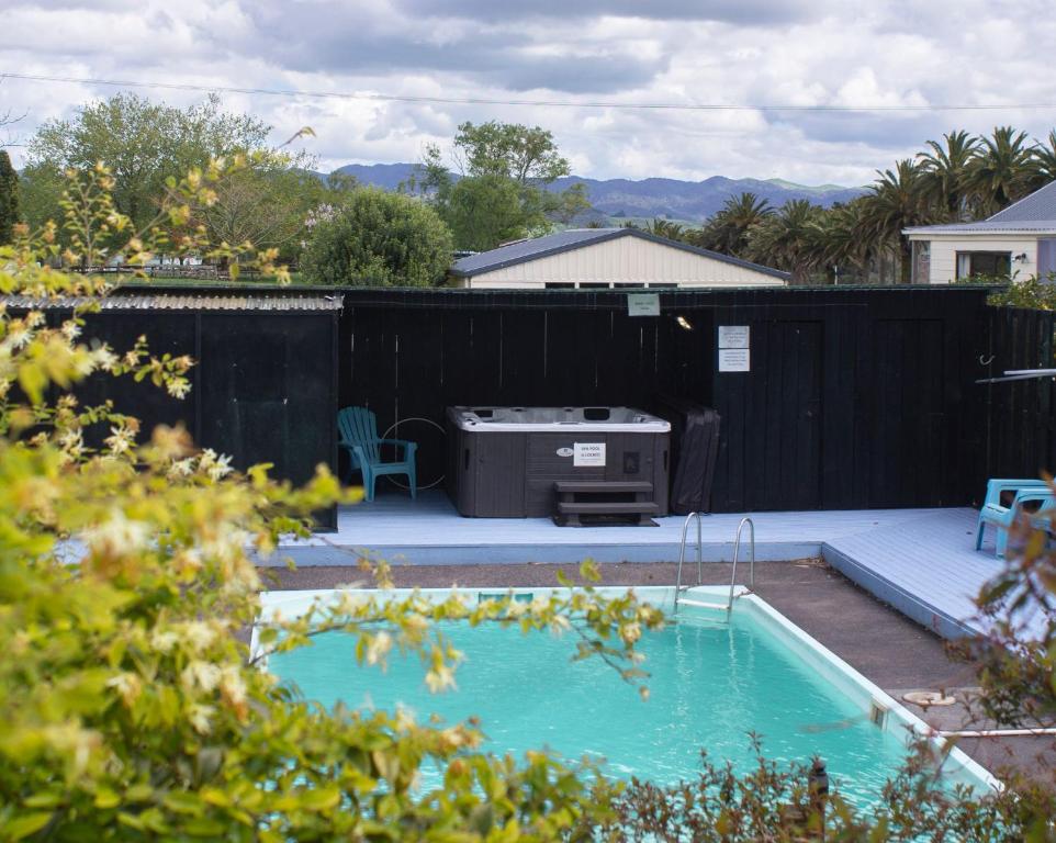 un patio trasero con piscina y parrilla en Palm Motel Waihi, en Waihi