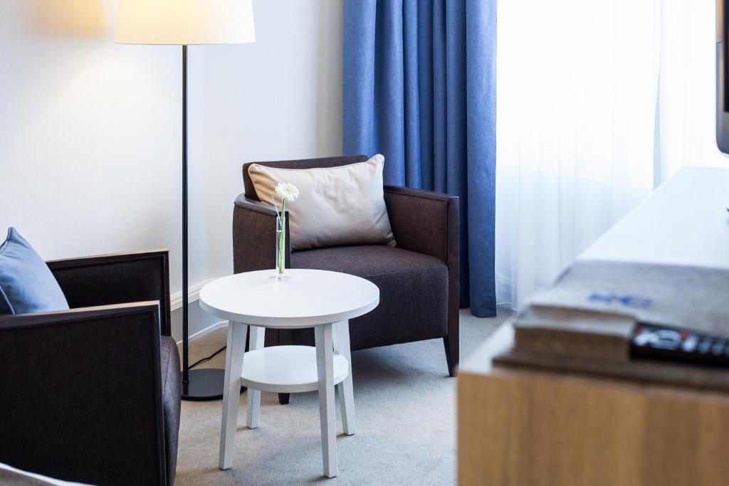 a room with a chair and a table and a bed at Hotel Neptun in Warnemünde