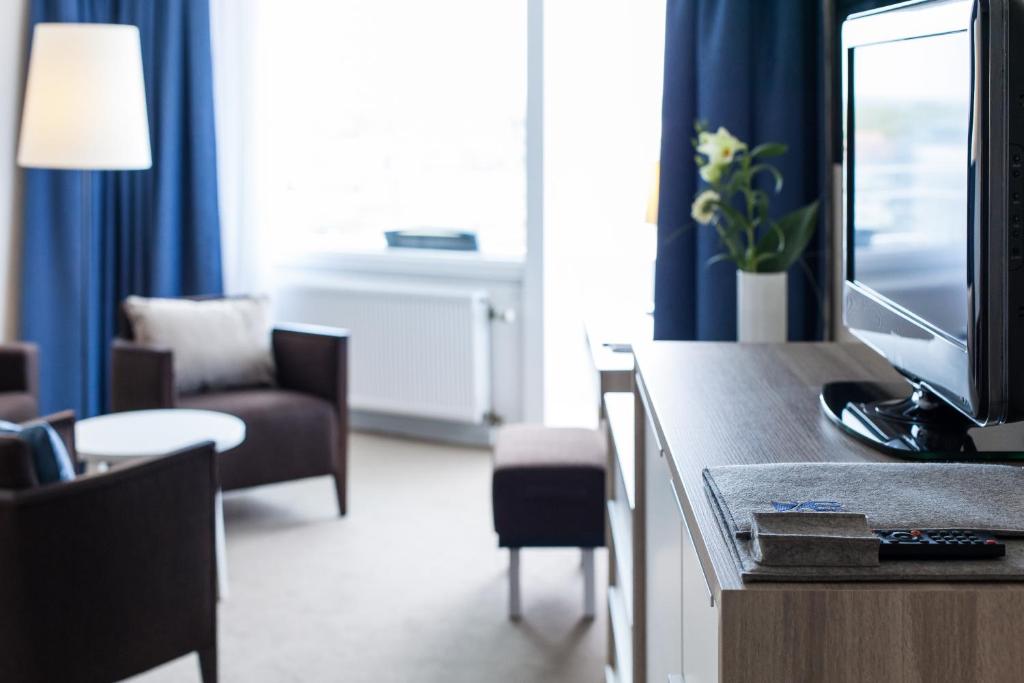 a hotel room with a television and a living room at Hotel Neptun in Warnemünde