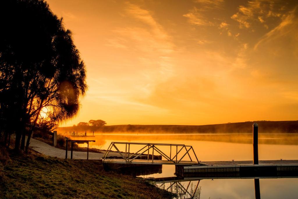 a sunset over a lake with a wooden dock at NRMA Warrnambool Riverside Holiday Park in Warrnambool