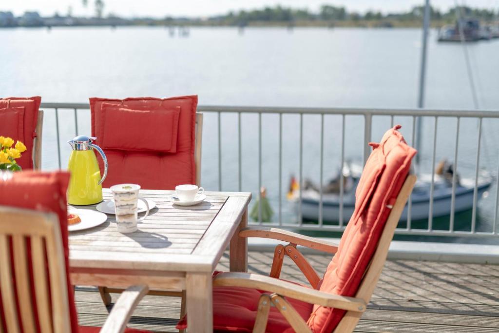 a wooden table and chairs on a deck near the water at Durchblick in Olpenitz