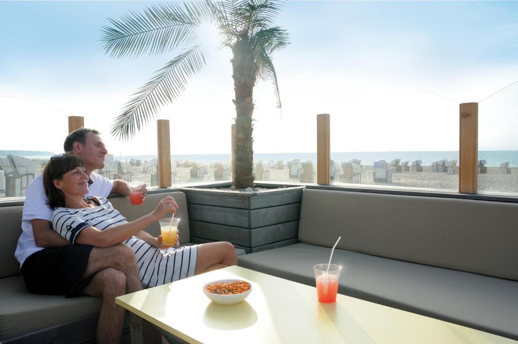 a man and a woman sitting on a couch with a table at Hotel Neptun in Warnemünde
