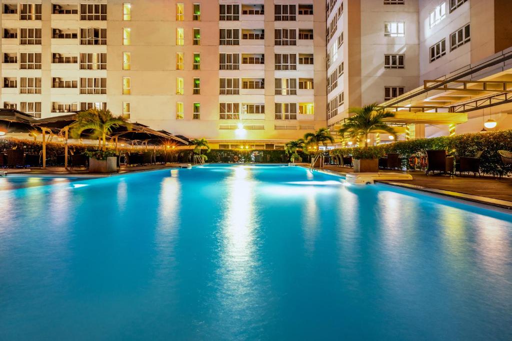 una gran piscina en una ciudad por la noche en Becamex Hotel Thu Dau Mot, en Thu Dau Mot