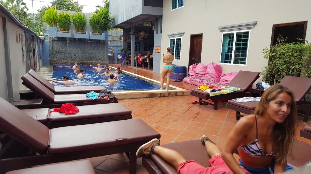 a woman laying on chairs in a swimming pool at Siem Reap Pub Hostel in Siem Reap