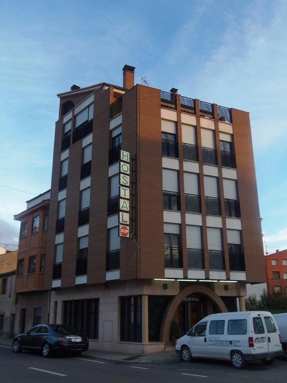 a building with two cars parked in front of it at Hostal Stop in Cantalejo