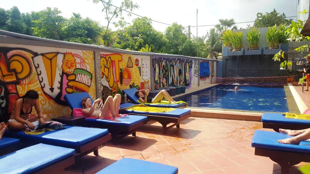 a group of people laying on benches next to a pool at Siem Reap Pub Hostel in Siem Reap