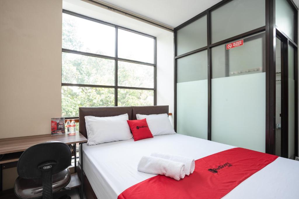 a bedroom with a bed with a desk and a chair at RedDoorz near Eka Hospital BSD City in Tangerang